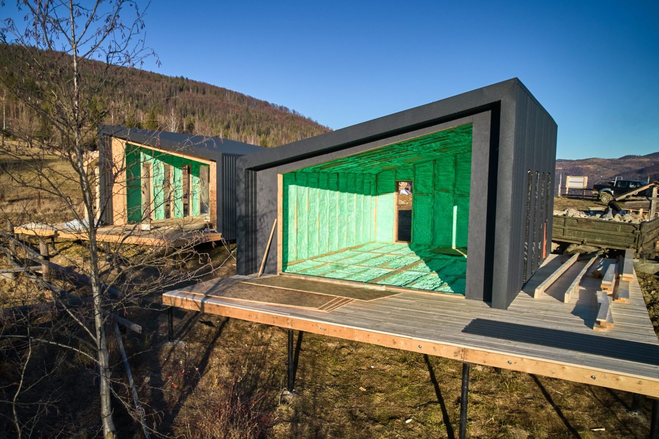 Drone view of two wooden frame houses in the Scandinavian style barnhouse thermal insulated by polyurethane foam. Construction and insulation concept.