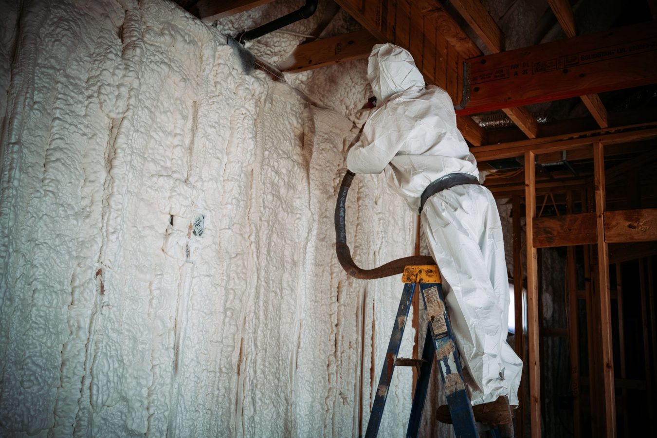 A worker doing spray foam insulation on the walls